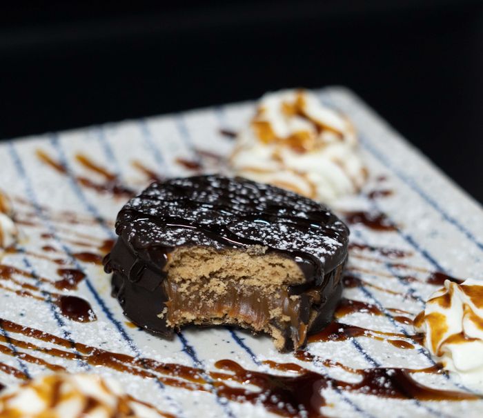 Alfajor argentino bañado en chocolate, relleno de dulce de leche, con una mordida