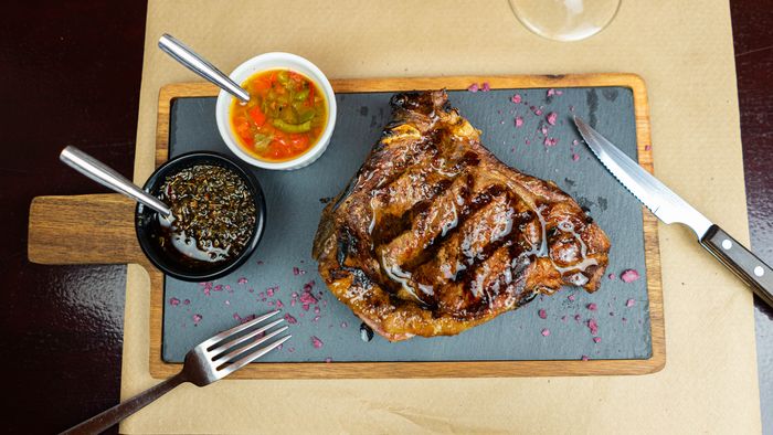 Entrecot a la parrilla bañado en salsa, servido con chimichurri y pickles