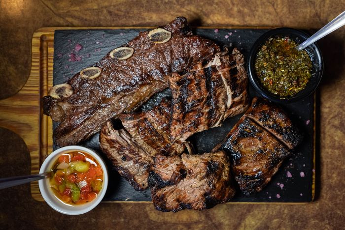 Parrillada típica argentina con asado de tira, churrasco y chimichurri, ideal para compartir
